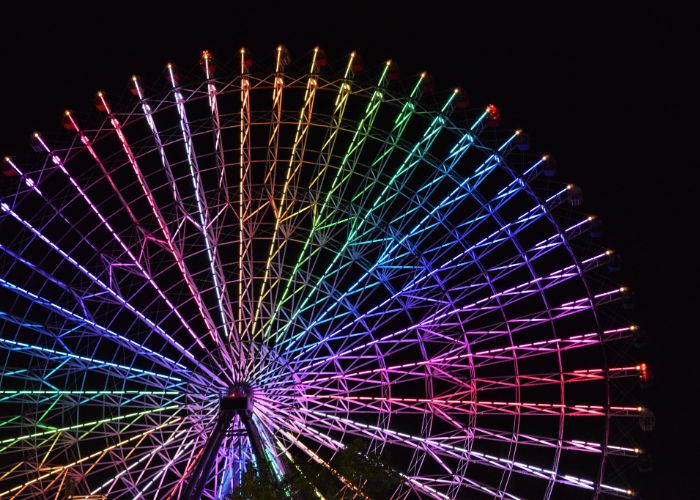 A close up of the Tempozan Ferris Wheel at night, lit up in multicolored LEDs
