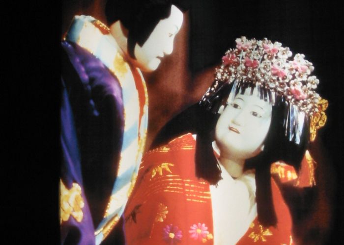 A close-up image of two bunraku puppets in kimono, one male and one female