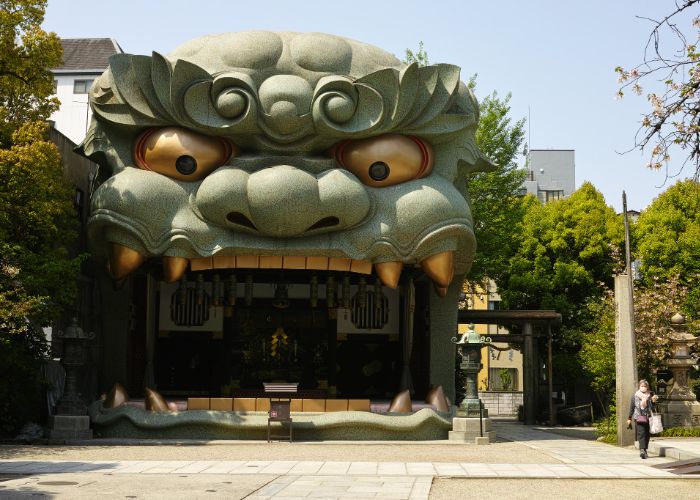 The pale green lion head building at Namba Yasaka Shrine, with huge gold eyes and an open mouth