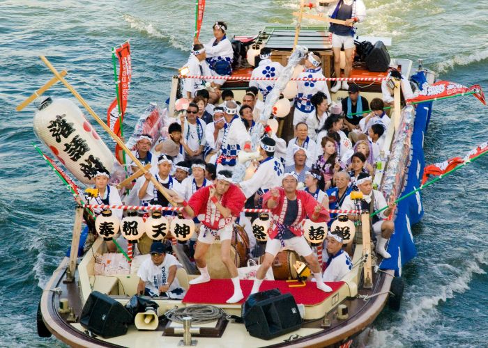 A boat full of festival-goers in traditional Japanese costume on a river
