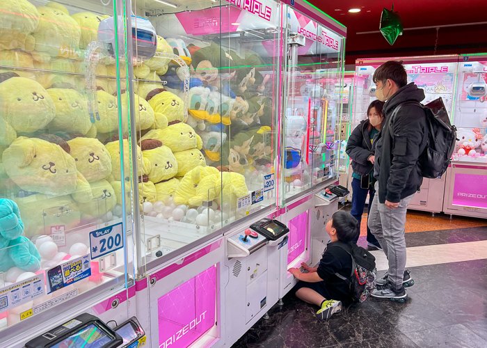 A family looks at a crane game in a Japanese arcade