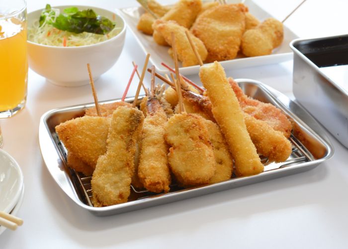 A pile of kushikatsu with cabbage salad and beer