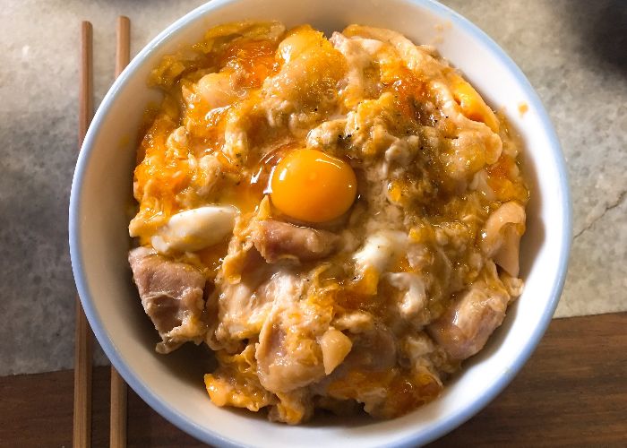 An overhead photo of a bowl of oyakodon, topped with strips of chicken and an egg yolk