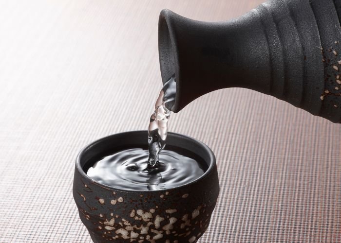 Sake being poured from a bottle into a small glass