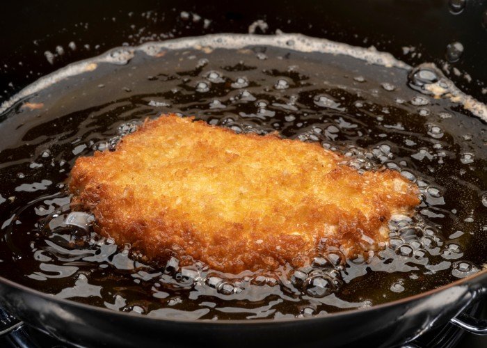 Tonkatsu being fried in a pot of oil