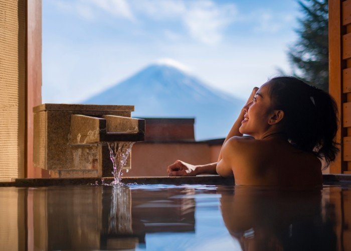 A women enjoying a onsen bath looking at a view of Mt. Fuji