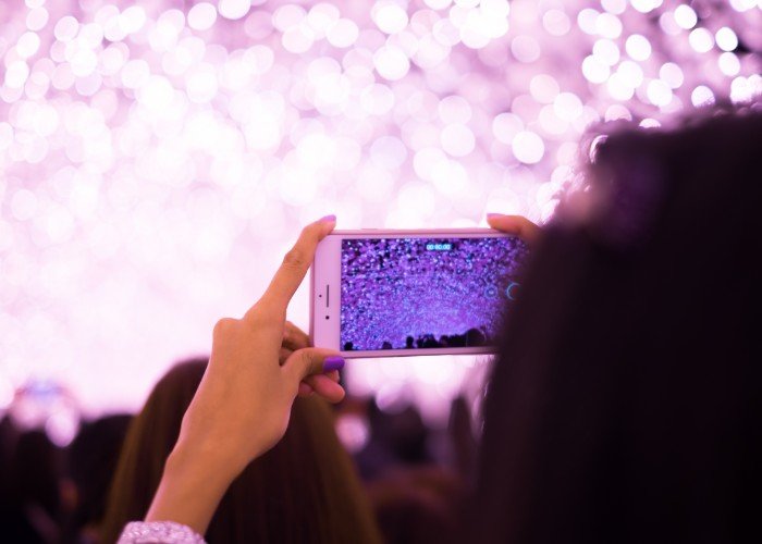 A women holds up a smartphone to take photos of an illumination display