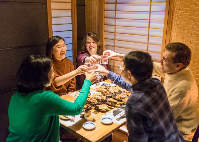 A group of friends toast at an izakaya