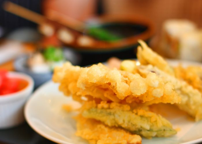 A close-up image of vegetable tempura coated in light brown batter