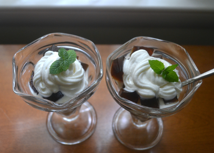 Two parfait glasses full of Japanese coffee jelly and whipped cream