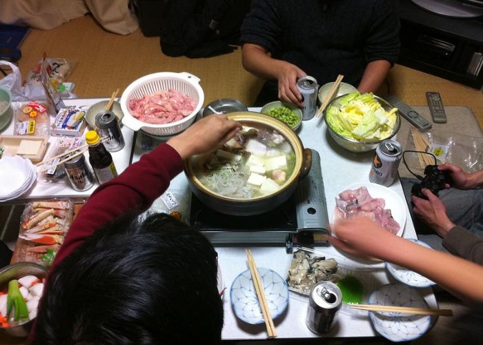 People having a nabe party with many ingredients gathered around a table