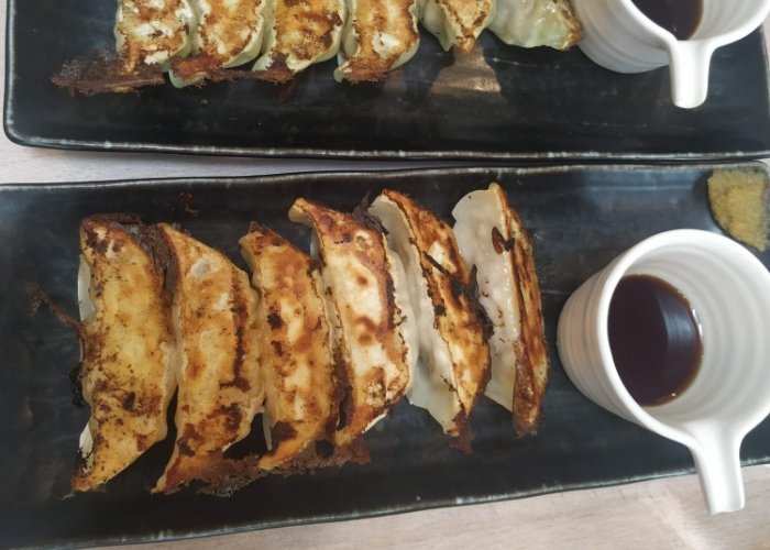 Two trays of gyoza with soy sauce