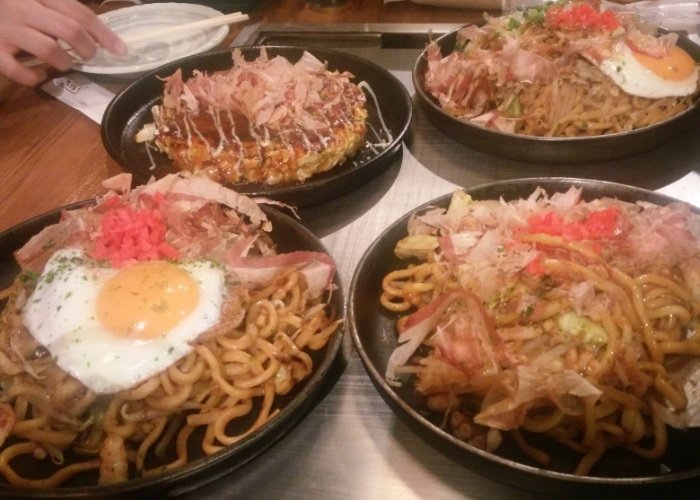 3 plates of yakisoba and one okonomiyaki on a hotplate