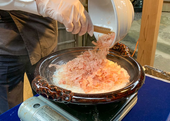 katsuobushi being ladled into a pot of rice