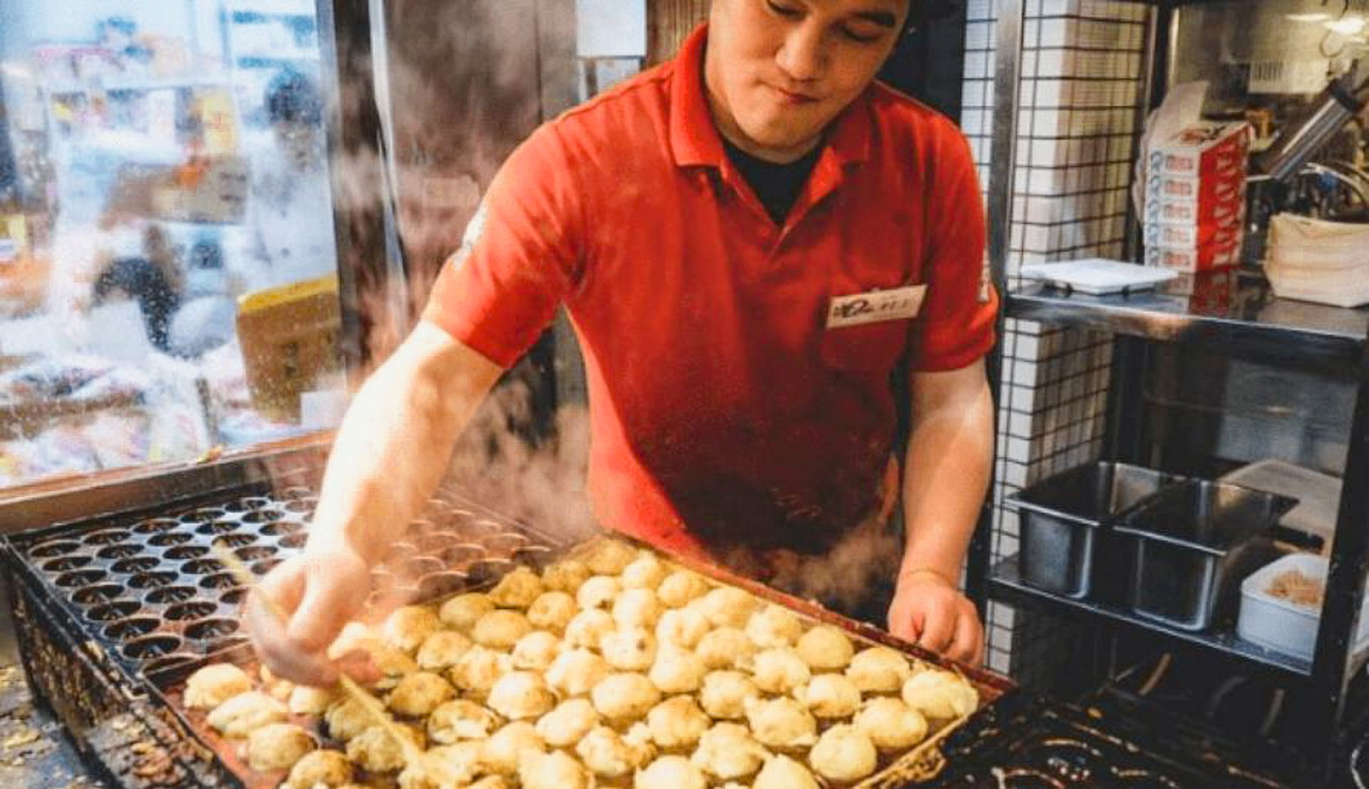 A vendor selling takoyaki in Kuromon Market.