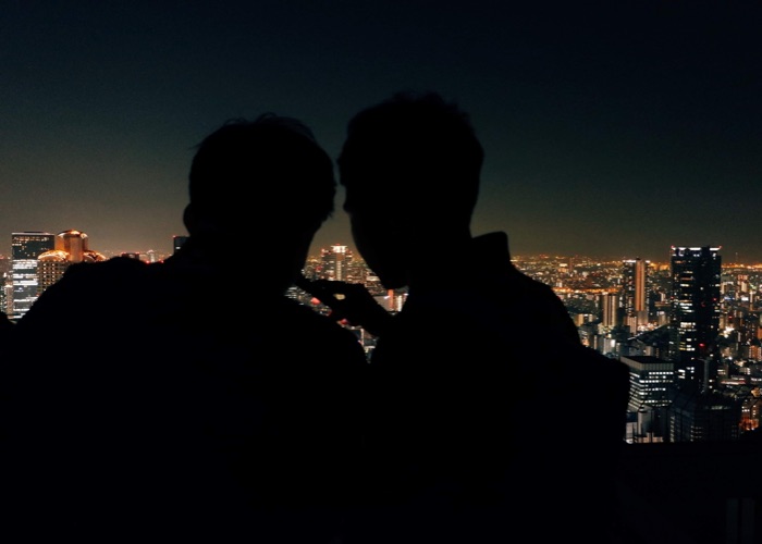 Silhouette of two people looking out at the night cityscape