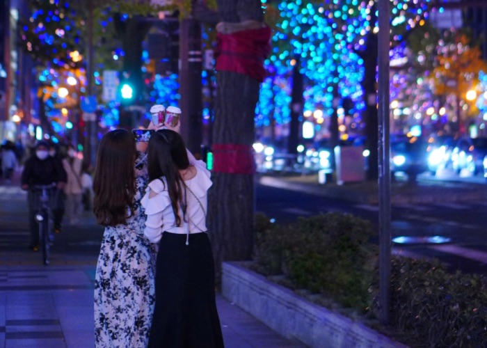 Two women taking a photo with tree illumination 