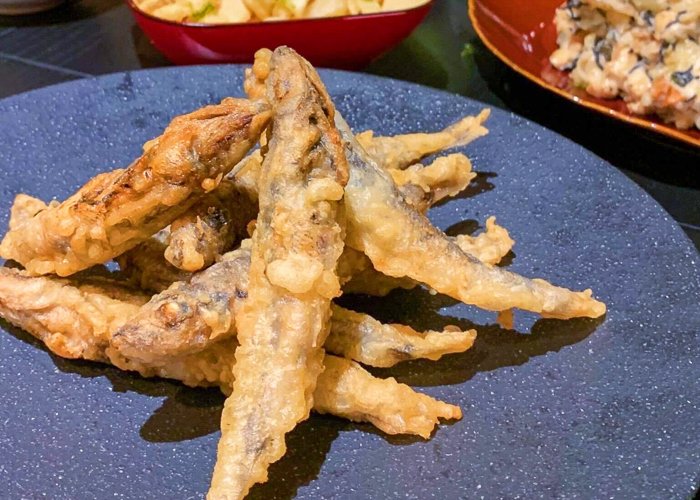 A pile of small tempura fish on a blue plate