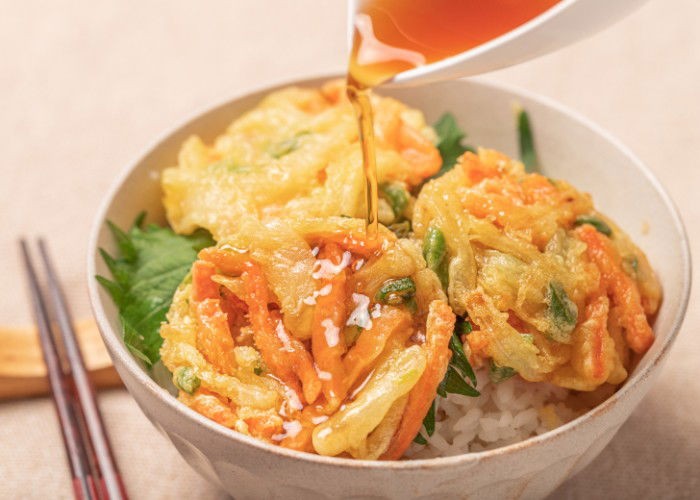 Sauce pouring over a kakiage donburi