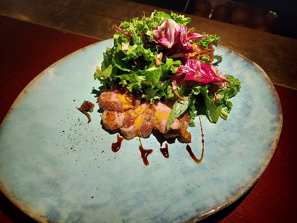 Gourmet salad with greens and balsamic drizzle on a blue plate
