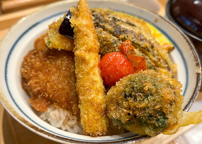 A bowl of fried pork and vegetables on rice