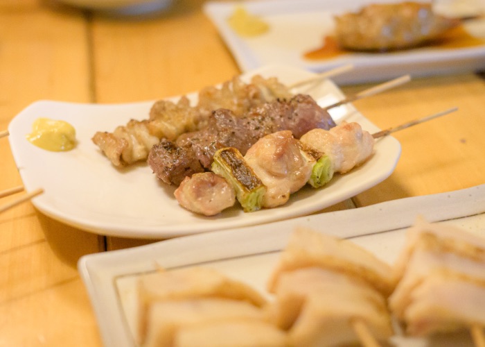 A plate of three skewers of yakitori on a table.