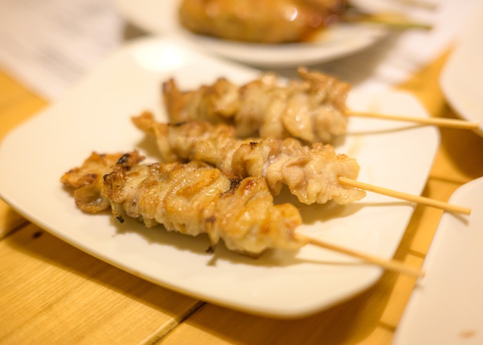 Three chicken skin yakitori skewers on a plate.