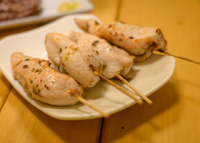 Four chicken tender yakitori skewers on a plate, topped with Shiso and stuffed with Japanese pickled plum.