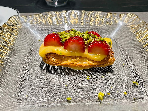 Delicious strawberry tart with pistachio topping on a glass plate