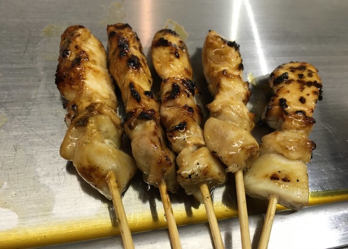Four skewers of chicken thigh Yakitori on a metal plate.