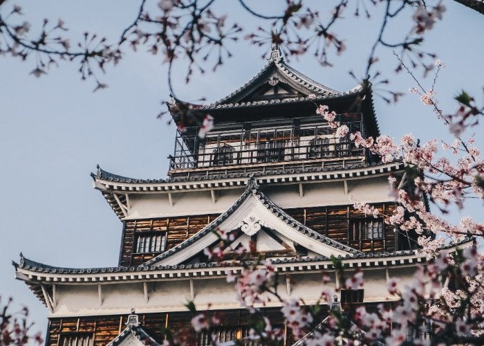 Hiroshima Castle surrounded by pink cherry blossoms on a clear day