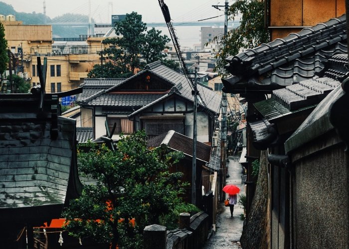 Sloping streets in Onomichi with someone holding and umbrella and walking away