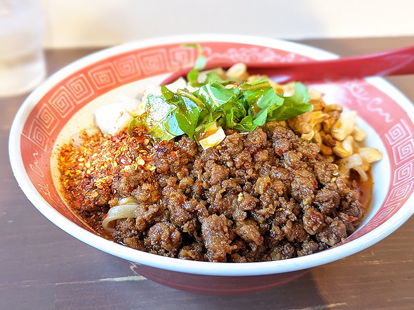 Spicy noodle dish with minced meat and fresh greens at a cozy restaurant