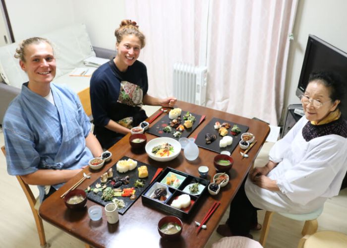 A couple posing with their teacher in front of their homemade tofu dishes during a cooking class in Japan
