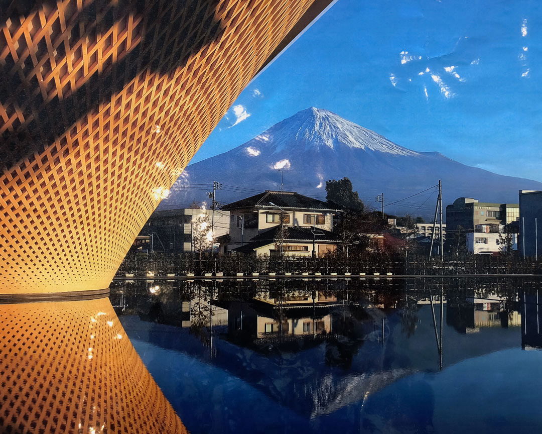 Looking up at Mt. Fuji from Fujinomiya, reflected against still water.