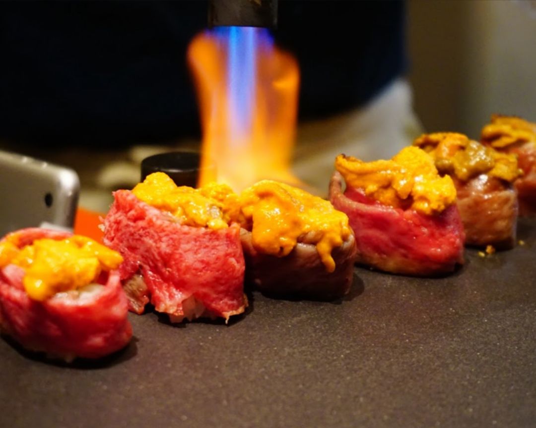 Sushi Chef Saisho flame-grilling a dish of sashimi
