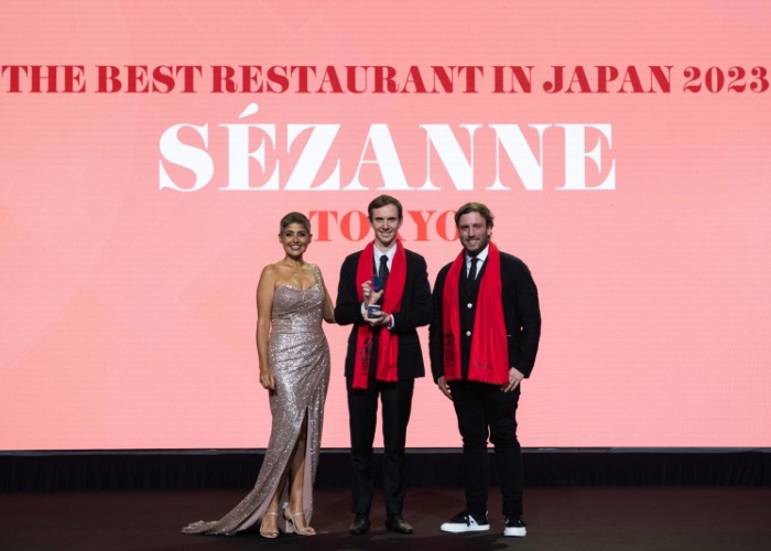 3 people standing infront of a sign "The best restaurants Japan 2023", while one man recieves award