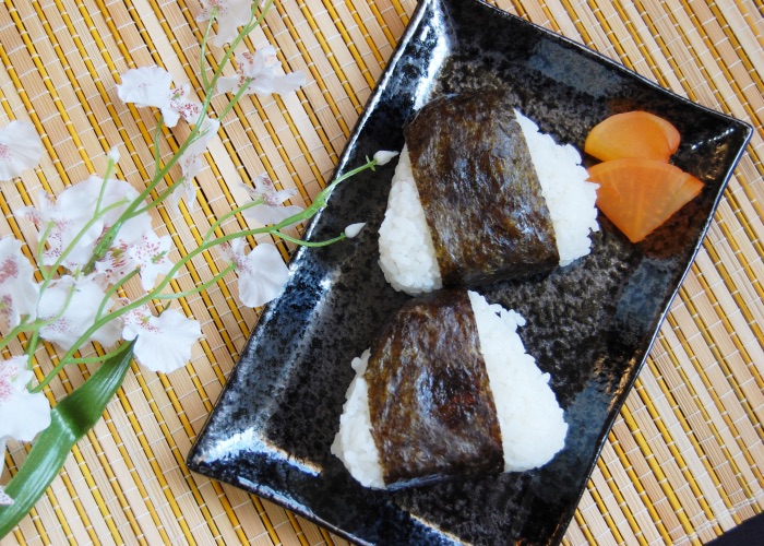Two seaweed-wrapped rice balls on a plate.