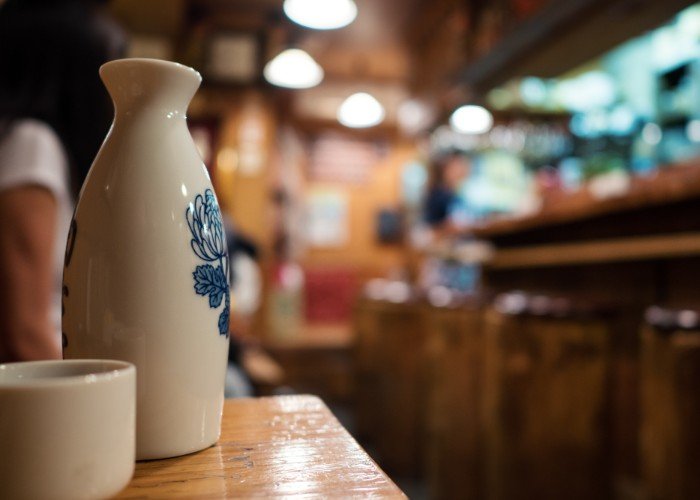 Sake bottle and cup with restaurant out of focus in the background