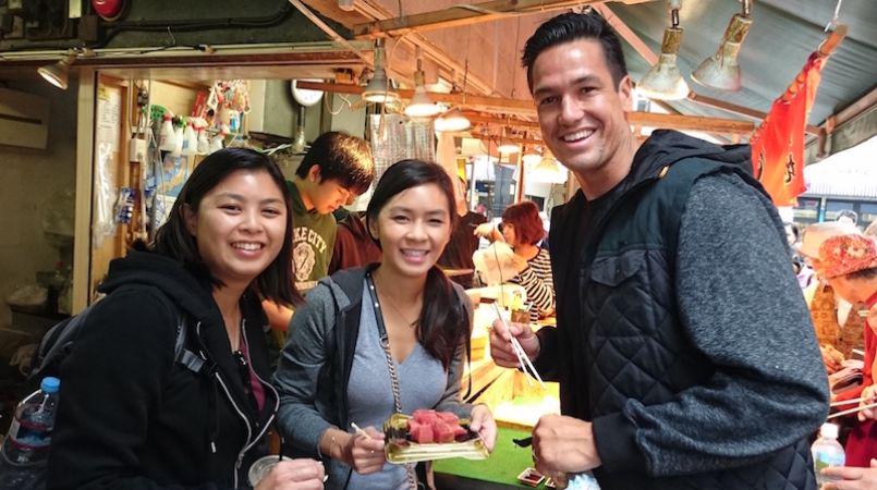 Three guests of a Tsukiji Market tour, preparing to enjoy fresh sushi.