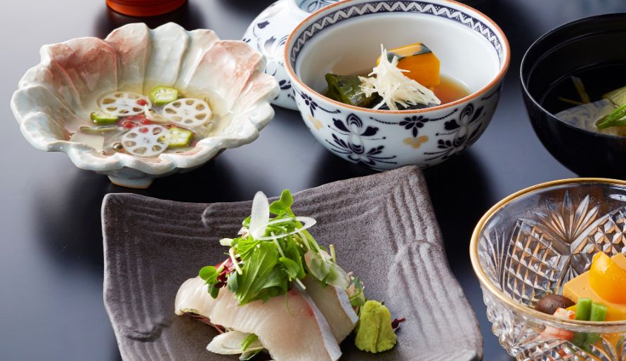 Traditional Japanese kaiseki meal with fish, vegetables, and lotus root.