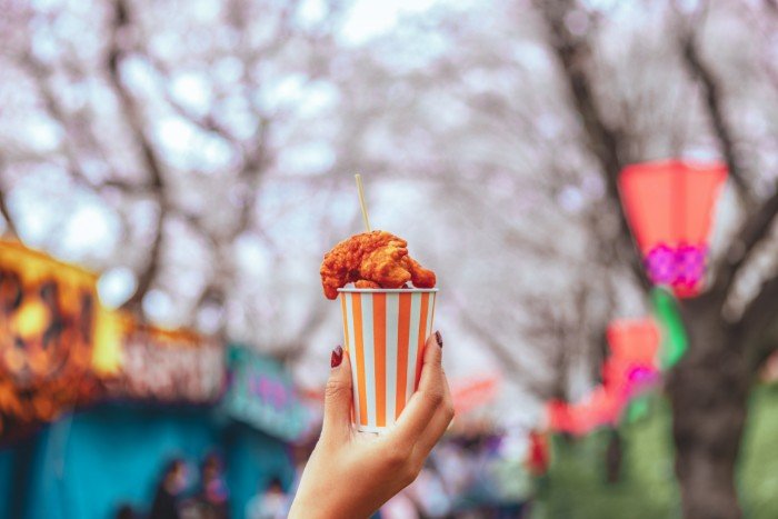 a hand holding a cup of karaage at a matsuri in Japan