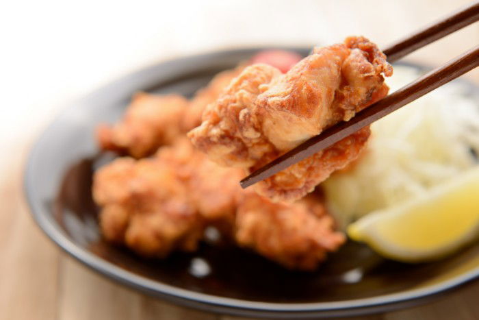 a piece of karaage held in chopsticks