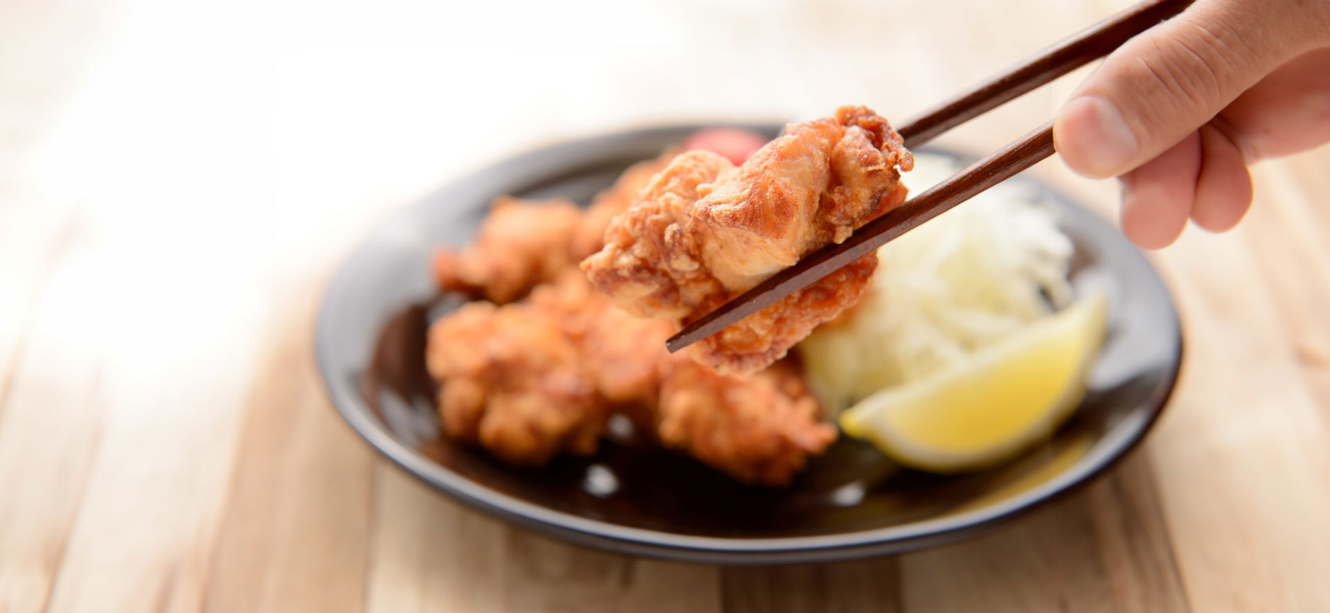 Crispy Japanese karaage being held with chopsticks on a plate