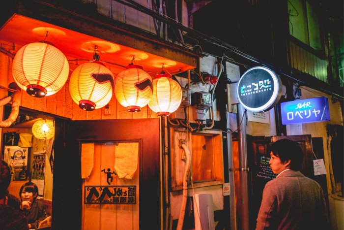 a man looks into a tiny bar in Shinjuku Golden Gai, in Tokyo