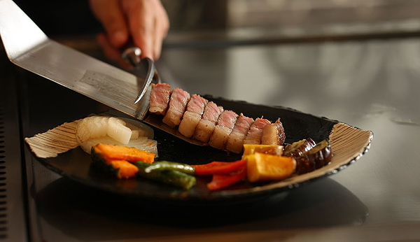 Chef serving gourmet steak with grilled vegetables on a stylish plate