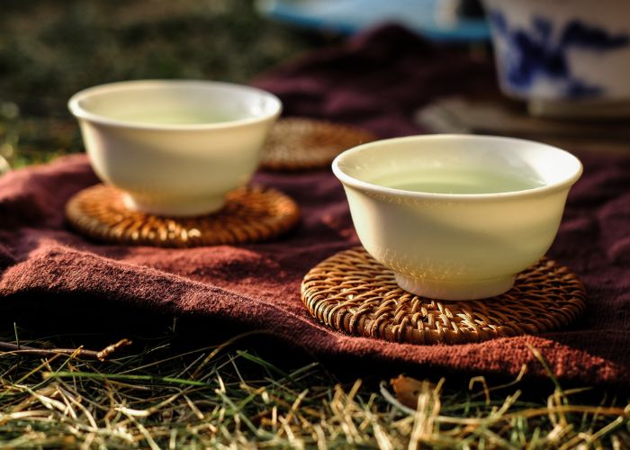 Two tea cups filled with tea with soft sunlight hitting them