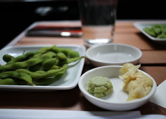 Plates of various foods, one in front has a blob of wasabi paste next to ginger