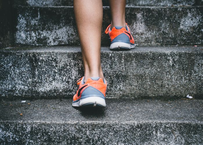 Bottom half of someone wearing sneakers walking up stone stairs