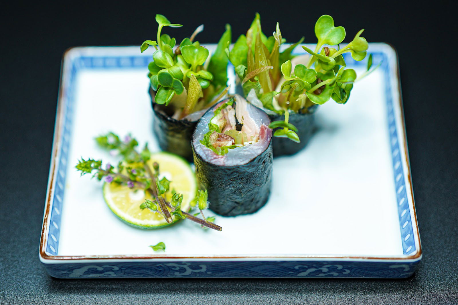 Elegant sushi rolls garnished with fresh greens on a decorative plate